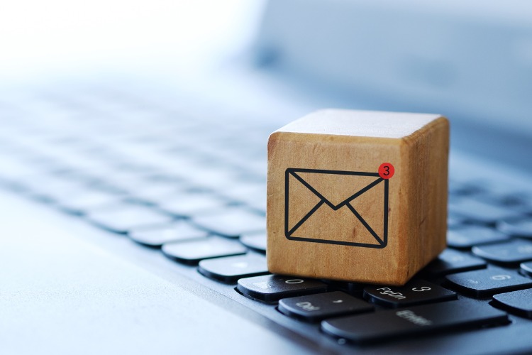 wooden square box sitting on a keyboard with an envelope symbolizing mailing equipment
