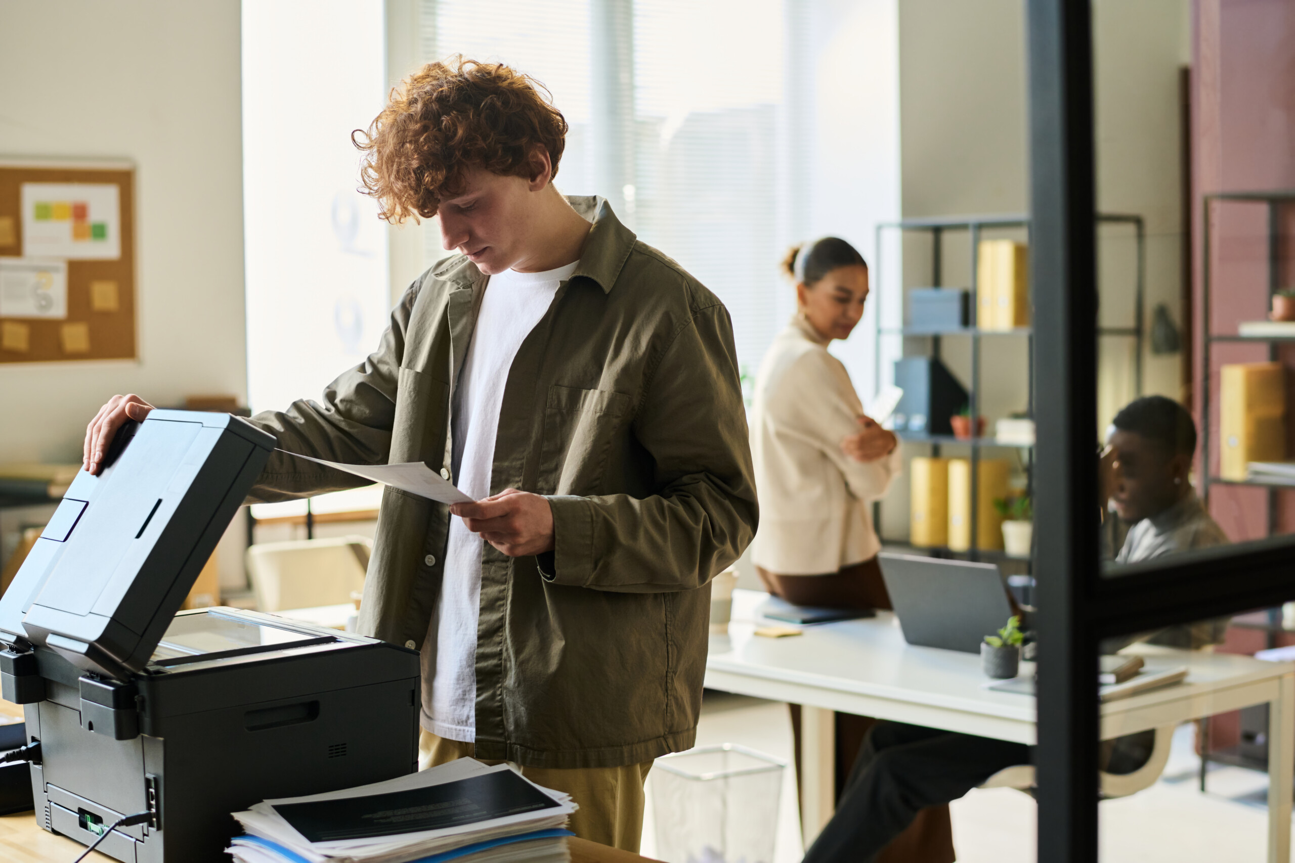 Office manager with financial papers An office setting with employees working efficiently; a young man uses a network copier, showcasing smooth and effective printing operations.
